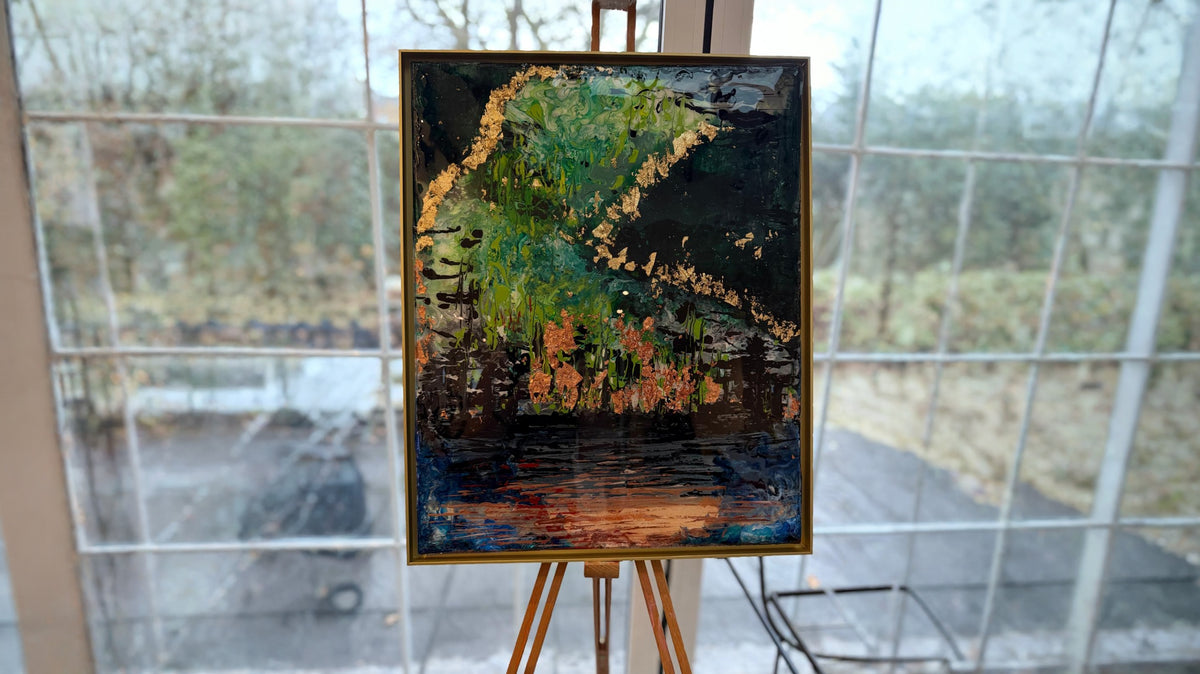 An oil painting of a forest landscape with green trees, orange foliage, and a dark background, displayed on a wooden easel in front of a large window.